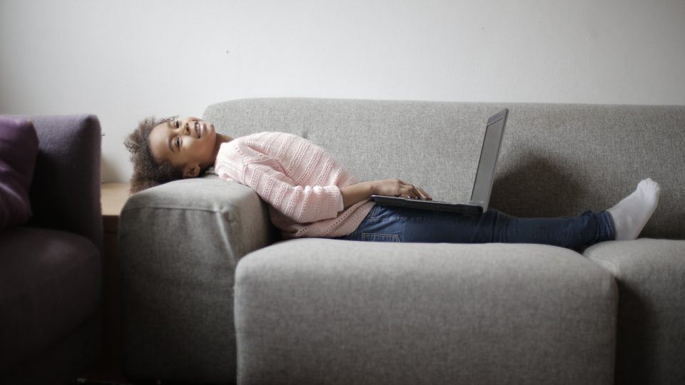 woman in pink and white stripe long sleeve shirt and blue denim jeans sitting on gray