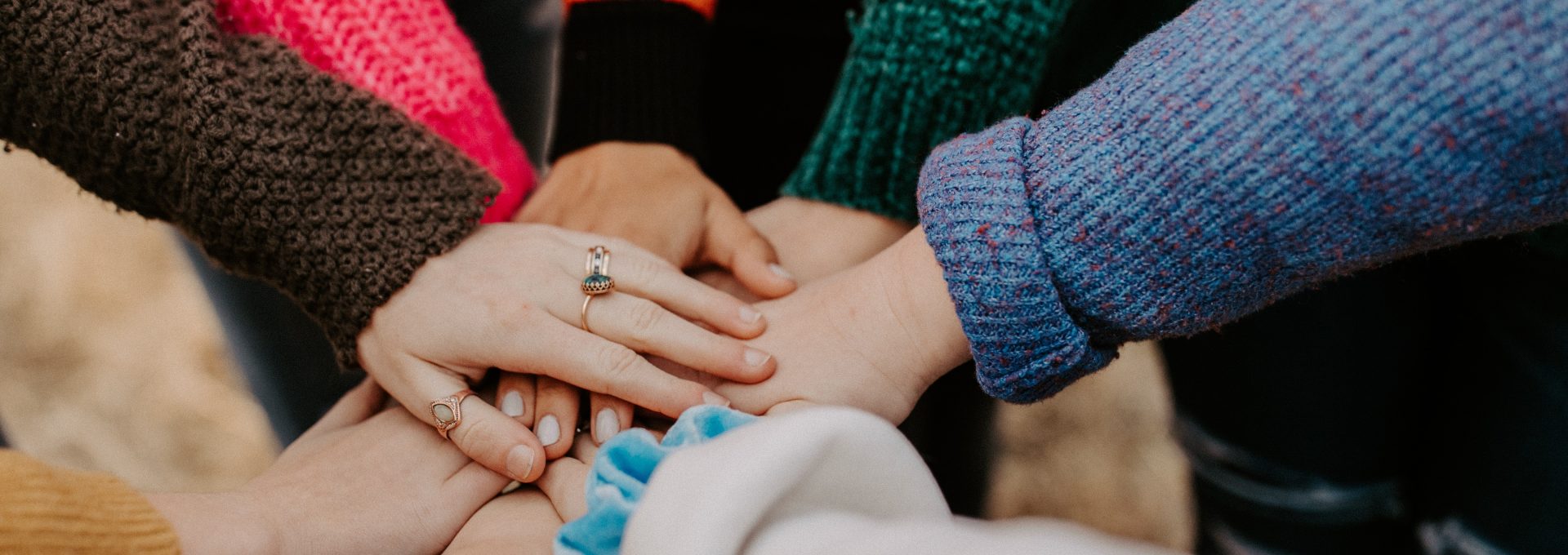 person in red sweater holding babys hand