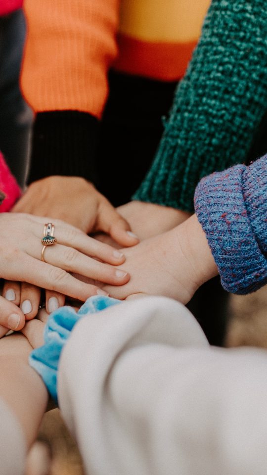 person in red sweater holding babys hand